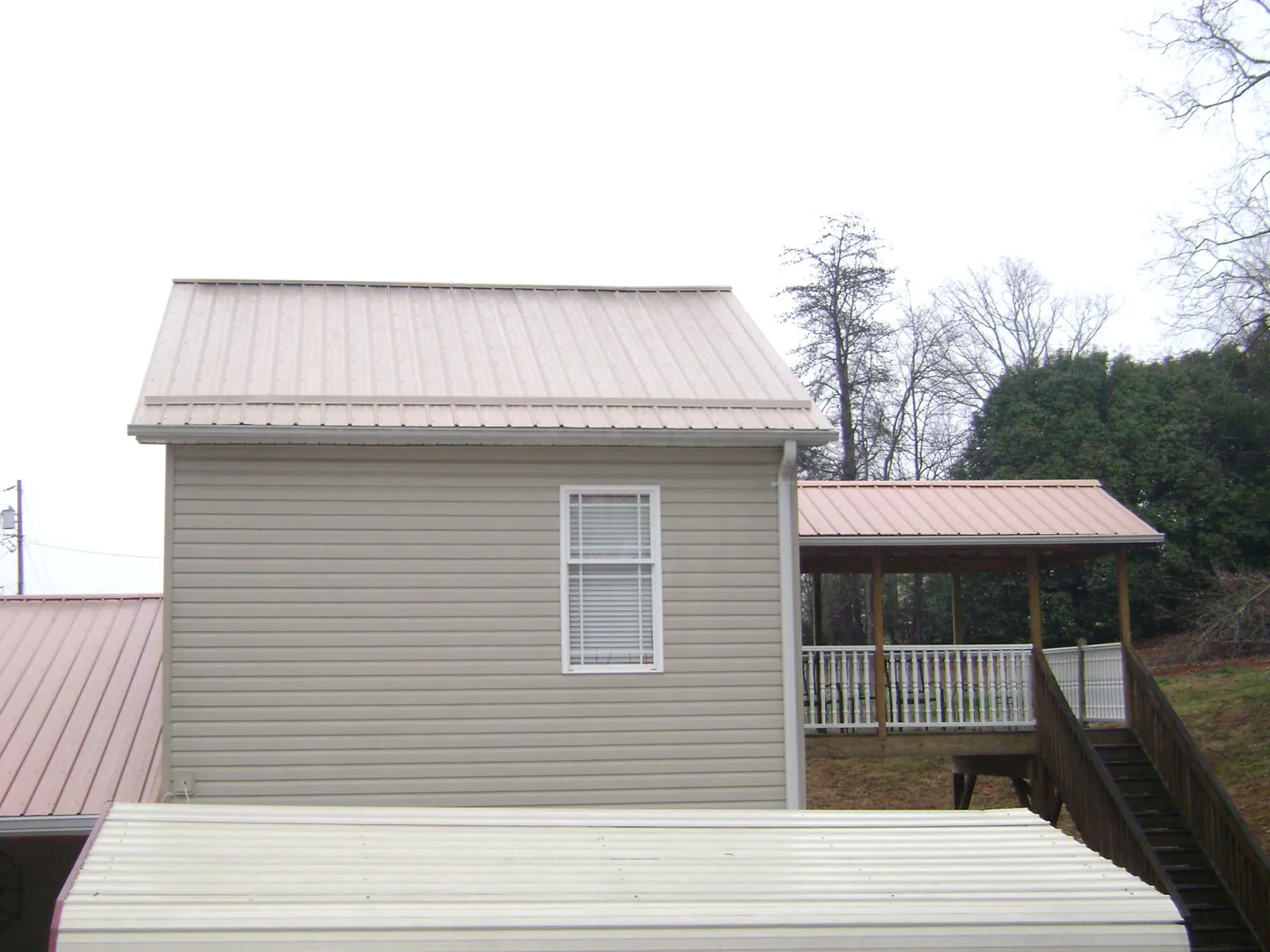 Tan metal roofs on a two story addition and attached porch, from a Roof Replacement job in Richmond